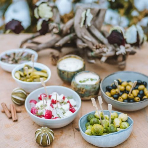 A rustic winter spread of appetizers on a wooden surface, featuring vegetables and dips.