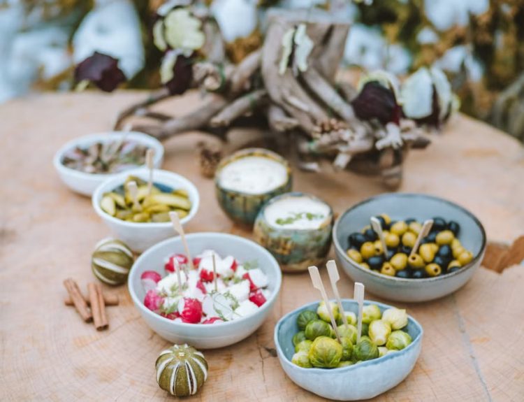 A rustic winter spread of appetizers on a wooden surface, featuring vegetables and dips.